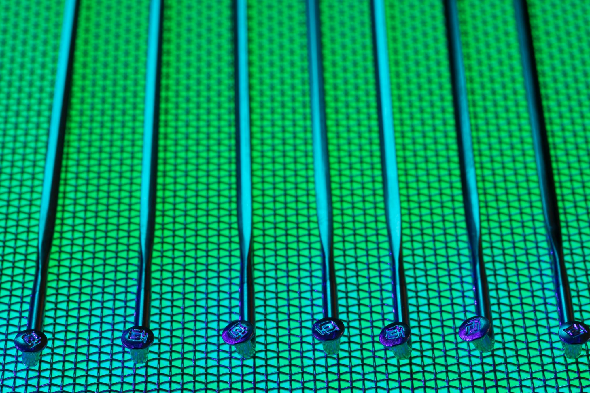 Vivid and detailed close-up of a patterned silicon wafer with vibrant green and blue colors.